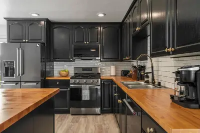 a kitchen with black cabinets and stainless steel appliances at 2-Story Sanctuary - Spacious Hot Tub - Billiards in Los Angeles