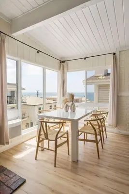 a dining room with a table and chairs and windows at Gorgeous Beachside Bliss Ocean View Walk2Strand in Manhattan Beach