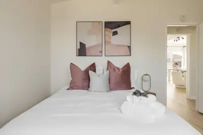 a bedroom with a large white bed with pink pillows at Gorgeous Beachside Bliss Ocean View Walk2Strand in Manhattan Beach
