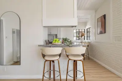 a kitchen with white walls and a counter with stools at Gorgeous Beachside Bliss Ocean View Walk2Strand in Manhattan Beach
