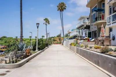 a sidewalk in front of a building with palm trees at Gorgeous Beachside Bliss Ocean View Walk2Strand in Manhattan Beach