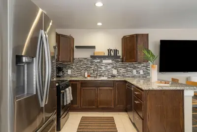 a kitchen with wooden cabinets and a stainless steel refrigerator at Surfers Dreams - 5min Drive to Beach with PoolTable in Long Beach
