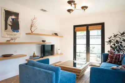 a living room with two blue chairs and a tv at Spanish-style garden Bungalow in Burbank