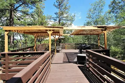 a wooden boardwalk with a pergola and a table at The Train Getaway Big Bear Lake in Big Bear Lake