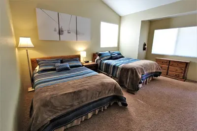 a bedroom with two beds and a dresser and two windows at Summit Ski Shack in Big Bear Lake