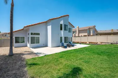 a white house with two chairs in a yard at Luxe Spacious Home Near Parks Fully Equipped in Riverside