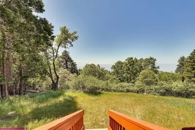 a wooden fence next to a field with trees at Stunning Deck Views Cozy Running Springs Cabin in Running Springs