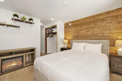 a bedroom with a white bed and a fireplace at Lily's Bear Cabin -Adorable Downtown Retreat Cottage in Big Bear Lake