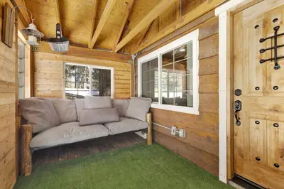 a couch sitting on a porch in a wooden house at Lily's Bear Cabin -Adorable Downtown Retreat Cottage in Big Bear Lake