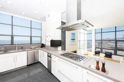 a kitchen with white cabinets and windows with a view at Stunning Panoramic Ocean Views Penthouse Hot Tub in Manhattan Beach