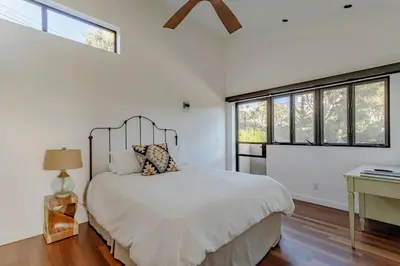 a bedroom with a bed and a desk and windows at Private Malibu Escape - Walk to Secluded Beach in Malibu