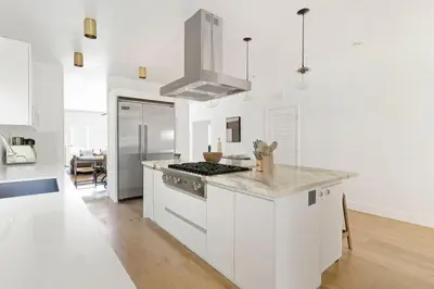 a kitchen with white cabinets and a stove top oven at Luxury Melrose District 3BR Retreat Pool Spa Gym in Los Angeles