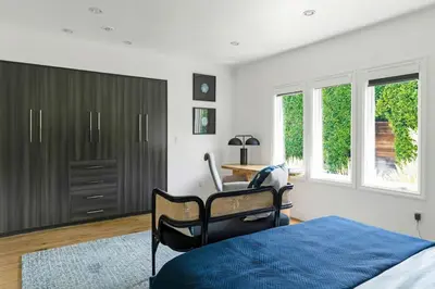 a bedroom with a bed and a desk and windows at Luxury Melrose District 3BR Retreat Pool Spa Gym in Los Angeles