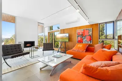 a living room with orange furniture and a fireplace at Hilltop Designer Midcentury Modern 4BR Pool HotTub in Los Angeles