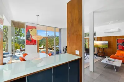 a kitchen and living room with a glass counter top at Hilltop Designer Midcentury Modern 4BR Pool HotTub in Los Angeles