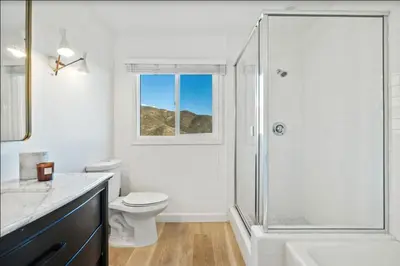 a white bathroom with a shower and a toilet at Luxe Malibu Retreat - Ocean Views, Hot Tub and Gym in Malibu