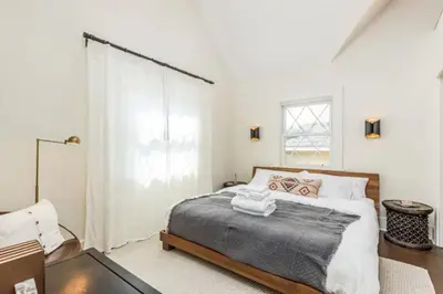 a white bedroom with a bed and a window at Chic Beach Bungalow 3 Blocks from the Sand in Manhattan Beach