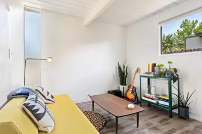 a living room with a yellow bed and a table at Eichler Mid-Century Perfect WFH, Relax and Entertain in Orange