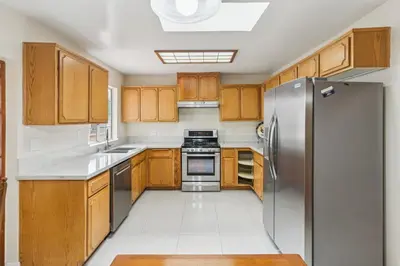 a kitchen with wooden cabinets and a stainless steel refrigerator at Russell House Near Hollywood & Griffith Park home in Los Angeles