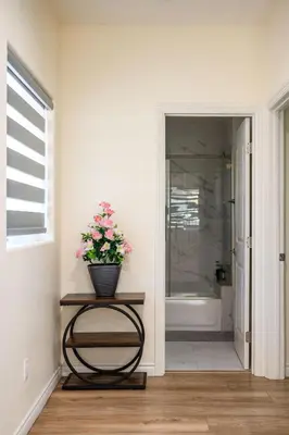 a bathroom with a vase of flowers on a table at Modern Getaway Near Pasadena & DTLA in Rosemead