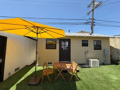 a patio with a table and chairs and an umbrella at Charming Casita near USC, SOFI, and Culver City in Los Angeles