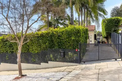 a fence in front of a house with palm trees at Spanish Bungalow in Trendy Los Feliz For Families in Los Angeles