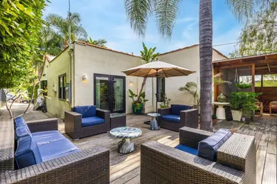 a patio with chairs and an umbrella and a table at Spanish Bungalow in Trendy Los Feliz For Families in Los Angeles