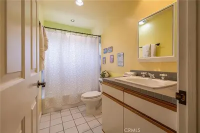 a bathroom with a sink and a toilet and a mirror at The Quiz Cottage Games & BBQ Outdoor Area! in Big Bear Lake
