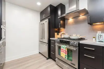 a kitchen with stainless steel appliances and black cabinets at Skyline Suites in North Hollywood
