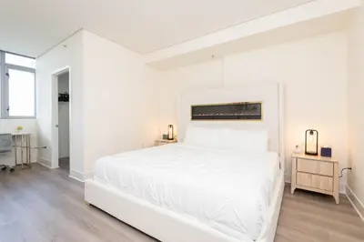 a white bedroom with a white bed and a window at Skyline Suites in North Hollywood