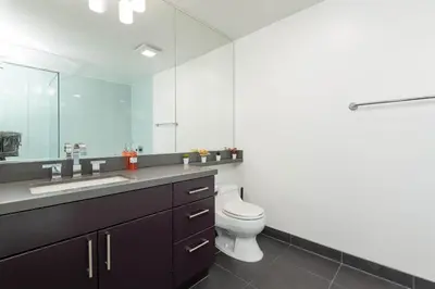 a bathroom with a toilet and a sink and a mirror at Skyline Suites in North Hollywood