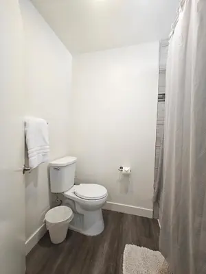 a white bathroom with a toilet and a shower at Skyline Escape 1-Bedroom with Balcony and Roof-Top Pool in Los Angeles
