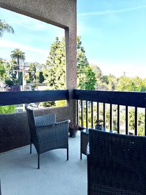 a balcony with two chairs and a view of trees at Skyline Escape 1-Bedroom with Balcony and Roof-Top Pool in Los Angeles