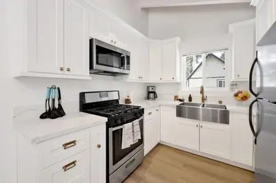 a kitchen with white cabinets and a stove top oven at Sueños Azules- Fawnskin Retreat Cottage in Big Bear in Fawnskin