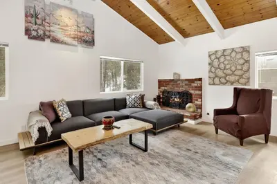 a living room with a couch and a table and a fireplace at Sueños Azules- Fawnskin Retreat Cottage in Big Bear in Fawnskin
