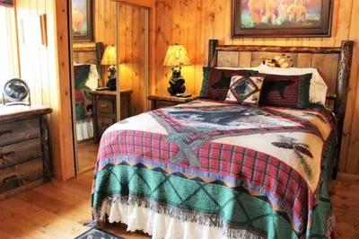 a bedroom with a bed in a room with wooden walls at Fire Pit & Steps to Village- Village Hideaway in Big Bear Lake