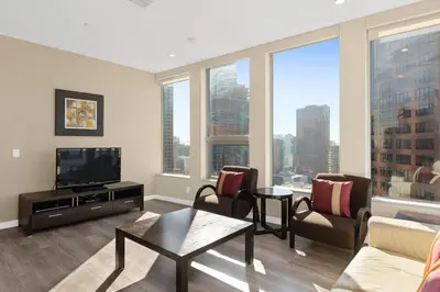 a living room with a flat screen tv and chairs at 2 Bed 2 Bath Stylish Luxury Premium High-Rise Apartment in Los Angeles