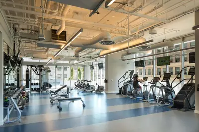 a gym with cardio equipment and people exercising in it at 2 Bed 2 Bath Stylish Luxury Premium High-Rise Apartment in Los Angeles