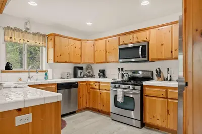 a kitchen with wooden cabinets and stainless steel appliances at Sea to Ski Retreat in Big Bear Lake