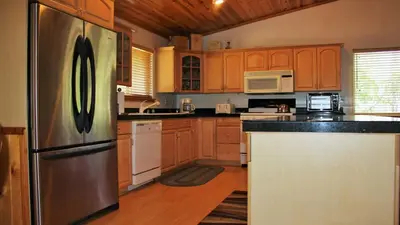 a kitchen with wooden cabinets and a stainless steel refrigerator at Hot Tub/Game Tables/Dogs OK - Aspen Glen in Big Bear Lake