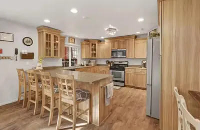 a kitchen with wooden cabinets and a large island with bar chairs at Moab Cozy Lane HotTub & Game Room with Pool Table in Big Bear Lake