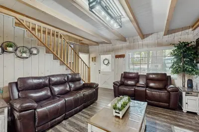 a living room with brown leather furniture and a staircase at Elevation Escape in Lake Arrowhead