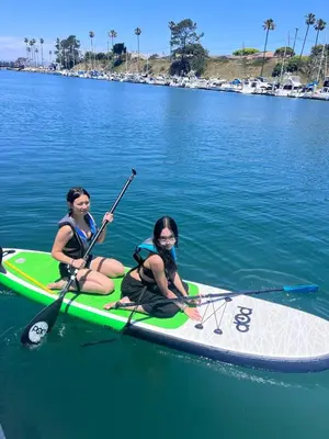 two women are sitting on a paddle board in the water at Serene Lakefront Escape in LA in Lake Hughes