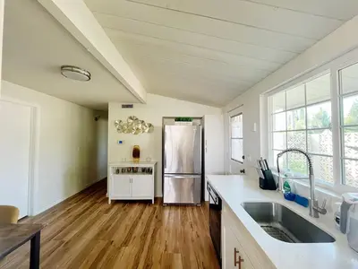 a kitchen with a stainless steel refrigerator and wooden floors at New Renovated 3B2B house in West Covina