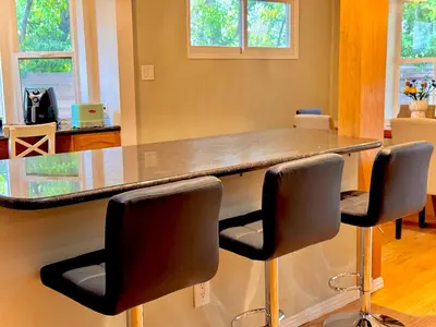 a kitchen with a counter with four bar stools at West LA - Family House & Private Yard - 10 mins from LAX & Beach in Los Angeles