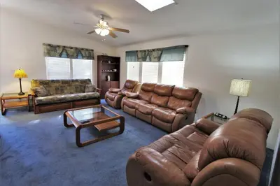 a living room with leather furniture and a ceiling fan at Bluebird Cottage in Big Bear Lake