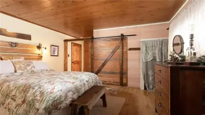 a bedroom with a bed and a wooden wall at Hot Tub, Near Village/Lake - Kelly`s Kottage in Big Bear Lake