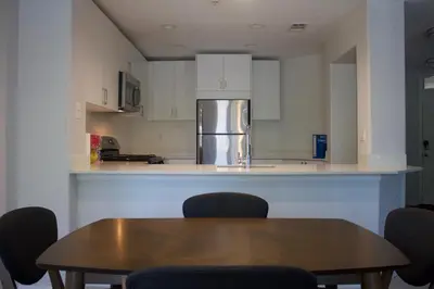 a kitchen with a table and chairs and a refrigerator at Luxury 3 Bedroom Apartment in Santa Clarita
