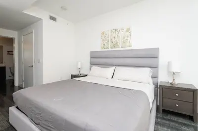 a white bedroom with a large bed and two night stands at 3-Bed High-Rise with Panoramic Views, Pool & Spa in Los Angeles