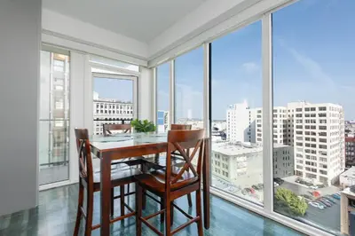 a dining room with a table and chairs and large windows at 3-Bed High-Rise with Panoramic Views, Pool & Spa in Los Angeles